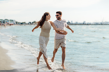 Image showing happy couple running along summer beach
