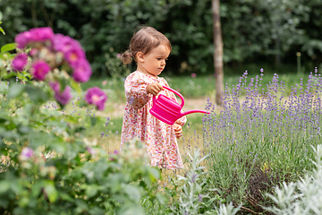 Image showing happy baby girl with watering can in summer garden