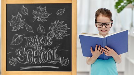 Image showing little student girl in eyeglasses reading book