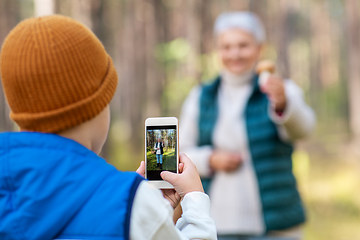 Image showing grandson photographing grandmother with mushroom