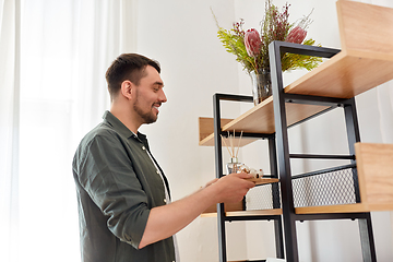 Image showing man placing aroma reed diffuser to shelf home