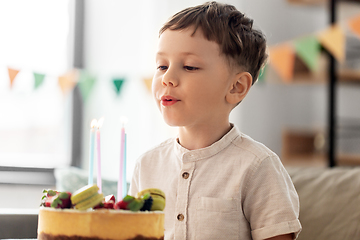 Image showing happy little boy blowing candles on birthday cake