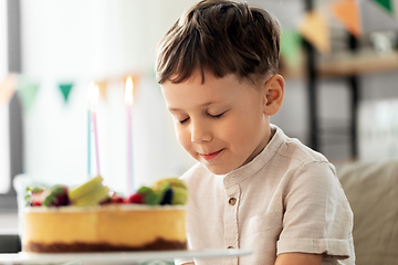 Image showing happy little boy blowing candles on birthday cake