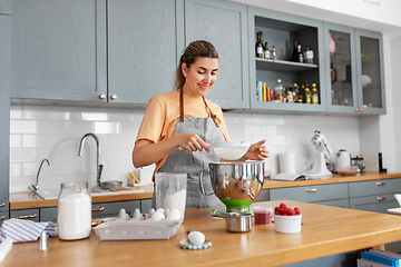 Image showing happy young woman cooking food on kitchen at home