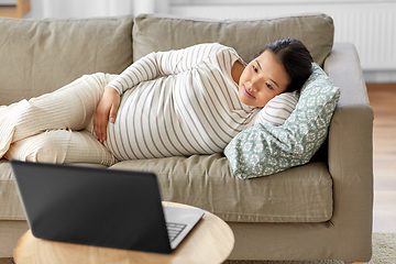 Image showing happy pregnant asian woman with laptop at home