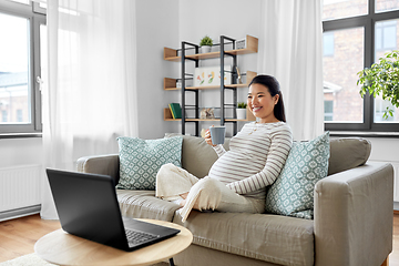 Image showing happy pregnant asian woman with laptop at home