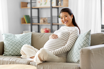 Image showing happy pregnant asian woman sitting on sofa at home