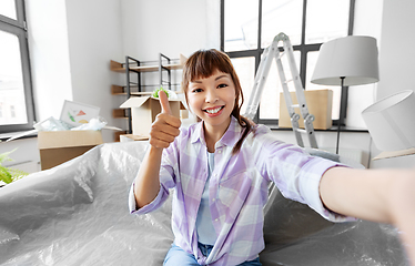 Image showing smiling asian woman taking selfie at new home