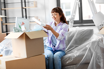 Image showing happy woman unpacking boxes and moving to new home