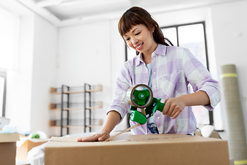 Image showing woman with adhesive tape packing box at new home