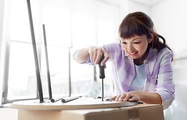 Image showing happy woman assembling coffee table at new home