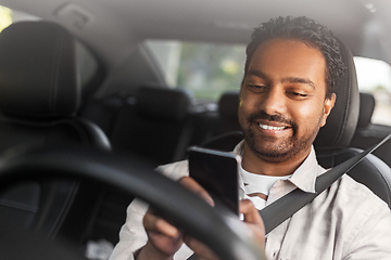 Image showing smiling indian man in car using smartphone