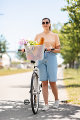 Image showing woman with food and flowers in bicycle basket