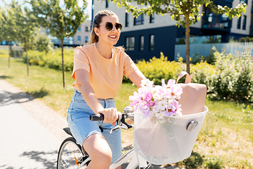 Image showing woman with flowers in bicycle basket in city