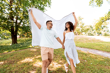 Image showing happy couple with picnic blanket at summer park