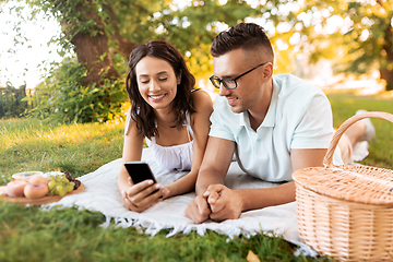 Image showing happy couple with smartphone at picnic in park