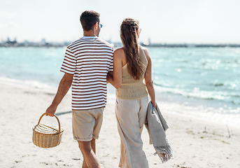 Image showing happy couple with picnic basket walking on beach