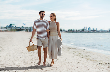 Image showing happy couple with picnic basket walking on beach