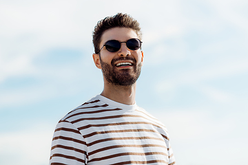 Image showing smiling young man in sunglasses over sky