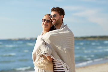 Image showing happy couple covered with blanket hugging on beach