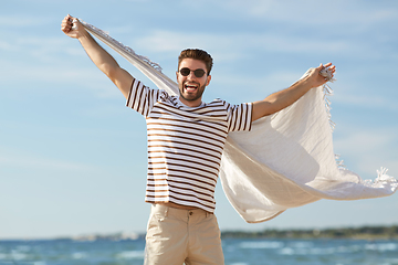 Image showing smiling man in sunglasses with blanket on beach