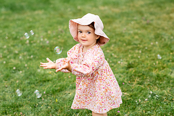 Image showing happy baby girl playing with soap bubbles outdoors