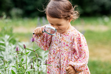 Image showing baby girl with magnifier looking at garden flowers