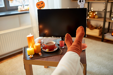Image showing young woman watching tv at home on halloween