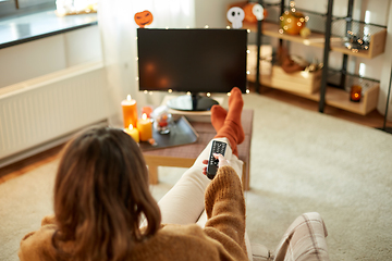 Image showing young woman watching tv at home on halloween