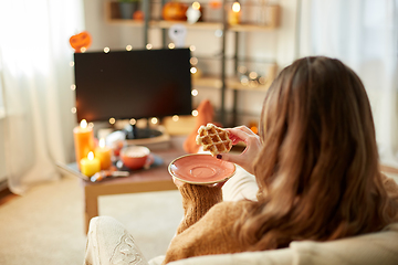 Image showing woman watching tv and eating waffle on halloween