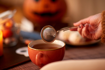 Image showing woman's hand with tea infuser and mug on halloween