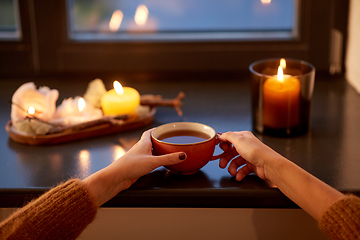 Image showing hands with cup of tea on window sill in autumn