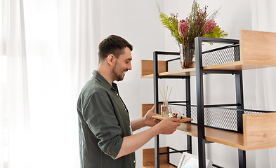 Image showing man placing aroma reed diffuser to shelf home