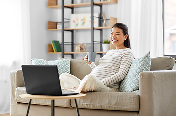 Image showing happy pregnant asian woman with laptop at home