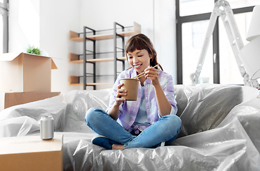 Image showing happy woman moving to new home and eating wok