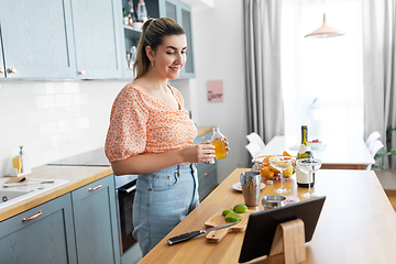 Image showing woman with tablet pc making cocktails at kitchen