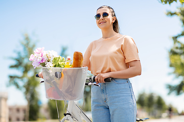 Image showing woman with food and flowers in bicycle basket