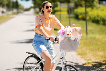 Image showing woman with flowers in bicycle basket in city