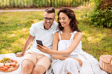 Image showing happy couple with smartphone at picnic in park