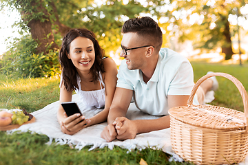 Image showing happy couple with smartphone at picnic in park