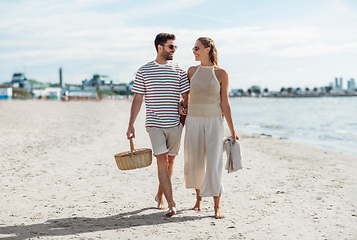 Image showing happy couple with picnic basket walking on beach