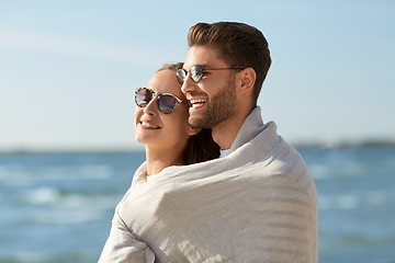 Image showing happy couple covered with blanket hugging on beach