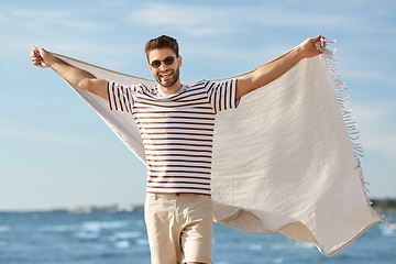 Image showing smiling man in sunglasses with blanket on beach