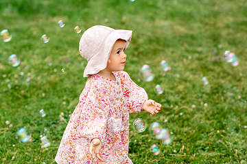 Image showing happy baby girl playing with soap bubbles outdoors