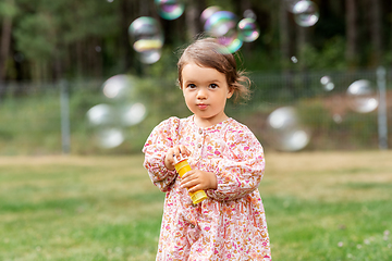Image showing happy baby girl blowing soap bubbles in summer