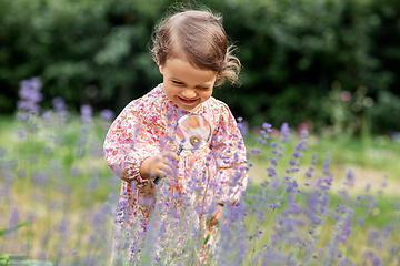 Image showing baby girl with magnifier looking at garden flowers