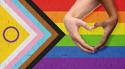 Image showing couple showing hand heart over progress pride flag