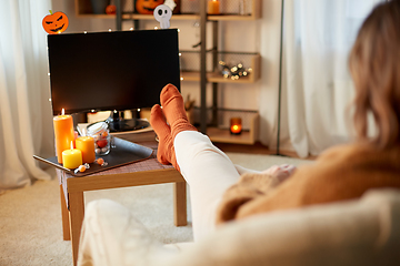 Image showing young woman watching tv at home on halloween