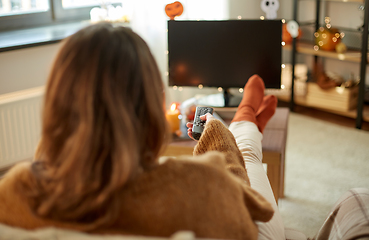 Image showing young woman watching tv at home on halloween