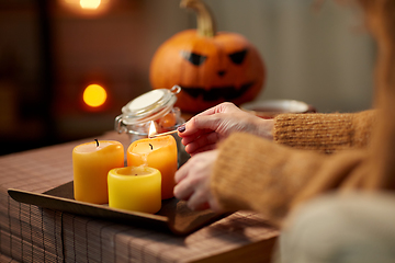 Image showing hand with match lighting candle on halloween